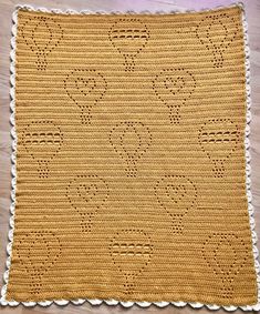 a yellow crocheted blanket with hearts on it