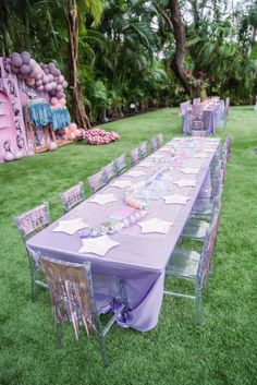 a long table set up with purple and pink decorations