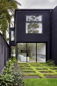 the modern house is surrounded by greenery and black walls, with large windows on each side