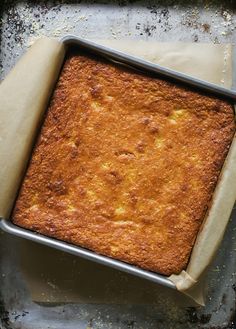 a pan filled with cake sitting on top of a metal counter next to a piece of parchment paper