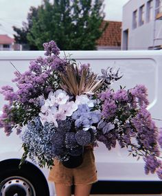 a woman holding a bouquet of flowers in front of a van