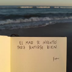 an open notebook with writing on it in front of the ocean