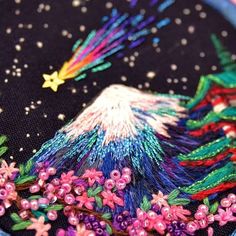 a close up of a colorful embroidered object on a black surface with stars and flowers