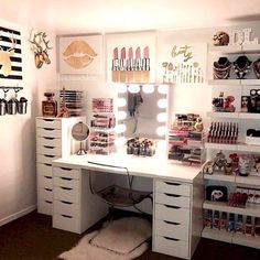 a white desk topped with lots of drawers under a mirror and lights on the wall