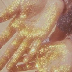 two people covered in gold glitters laying on the ground with their hands spread out