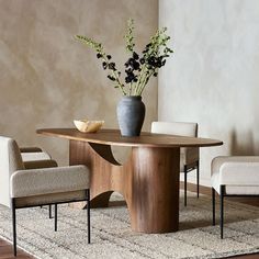 a vase with flowers sitting on top of a wooden table next to two white chairs