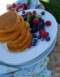 some pancakes and berries are on a white plate