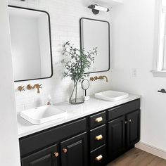 a bathroom with two sinks, mirrors and a plant in a vase on the counter