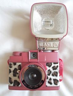 a pink polaroid camera sitting on top of a bed