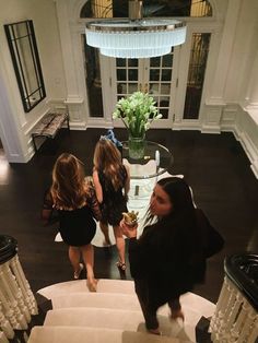 three girls are walking down the stairs in a house with white walls and black floors