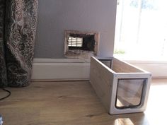 a microwave oven sitting on top of a wooden floor next to a window sill