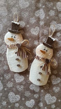 two snowmen wearing hats and scarfs made out of rock sitting on top of a table