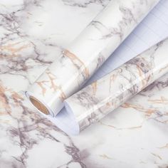 two rolls of white and gold marble paper on top of each other, with one roll sticking out of it