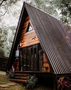 a - frame cabin in the woods with stairs leading up to it's front door