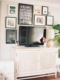 a white entertainment center with pictures on the wall