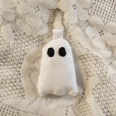 a white bag with black eyes hanging from a chain