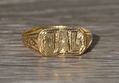 a gold signet ring with the word dad engraved in it on a wooden surface