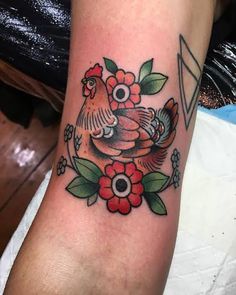 a tattoo on the arm of a woman with flowers and roosters in her arms