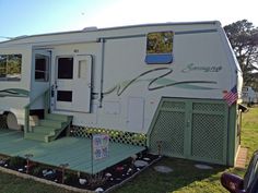 an rv parked on the grass with stairs leading up to it's front door