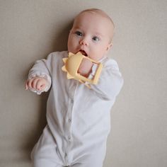 a baby with a pacifier in its mouth laying on the floor next to a wall