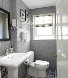 a white toilet sitting next to a sink in a bathroom under a mirror and framed pictures on the wall