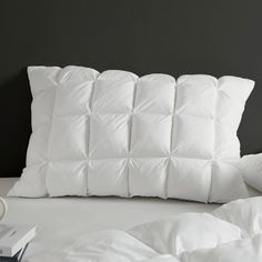 a white pillow sitting on top of a bed next to pillows and a book in front of it