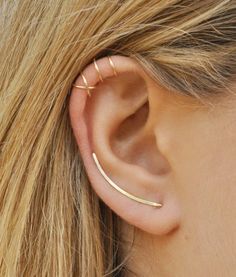 a woman's ear is shown with two thin bar earrings