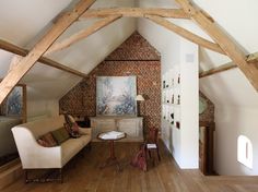 a living room filled with furniture and exposed beams in an atticed building that has wood flooring