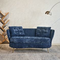 a blue couch sitting on top of a carpeted floor next to a book shelf