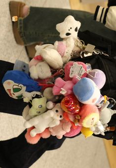 a bunch of stuffed animals are in someone's hand on the floor next to a purse