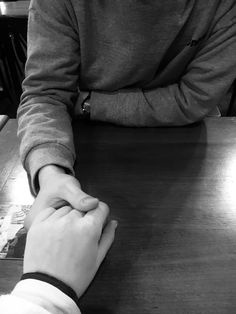 two people sitting at a table with their hands on each other's wrists