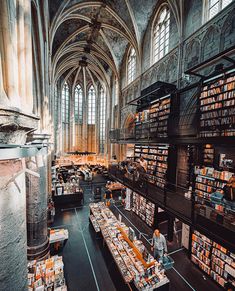 a large room filled with lots of books on top of shelves next to tall windows