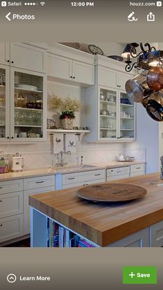 a large kitchen with white cabinets and wooden counter tops, an island in the middle