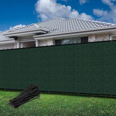 a black umbrella laying on the grass in front of a house with a green fence