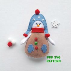 a felt penguin ornament sitting on top of a white surface next to snowflakes