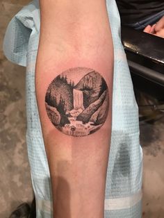 a person with a tattoo on their arm has a bear and waterfall in the background