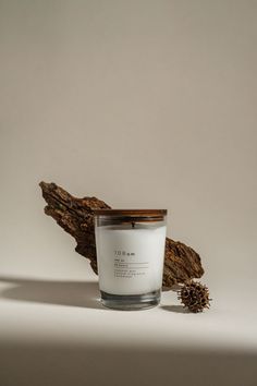 a candle sitting on top of a piece of wood next to a small pine cone