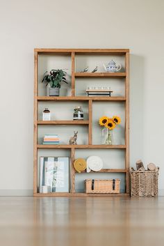 a wooden shelf filled with lots of books and vases next to a basket full of sunflowers