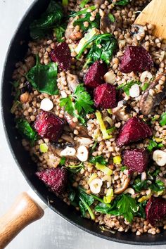 beet, spinach and farro salad in a skillet with a wooden spoon