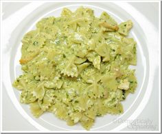 a white plate topped with pasta and broccoli covered in pesto cheese sauce