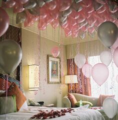 balloons and streamers fill the air above a bed in a room decorated for a party