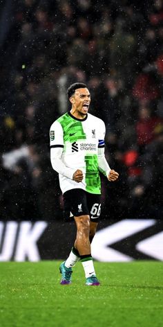 a soccer player is running on the field in the rain with his mouth wide open