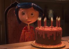 a girl with blue hair standing in front of a cake that has lit candles on it