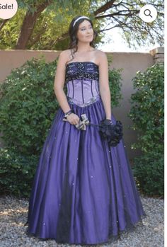 a woman wearing a purple dress standing in front of bushes