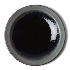 a black and gray bowl with white liquid in the center on a white surface, viewed from above