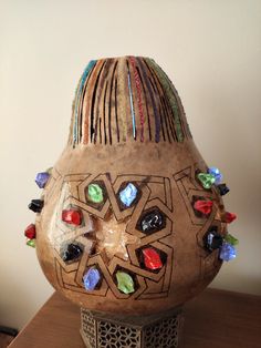 a decorative vase sitting on top of a wooden table covered in glass beads and stones