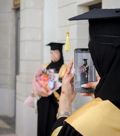 a woman taking a photo with her cell phone while other people in graduation gowns watch