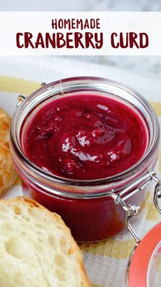 homemade cranberry curd in a glass jar with bread on the table next to it