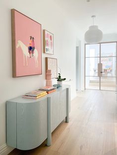 a living room with two paintings on the wall and a table in front of it