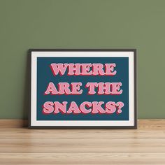 there are the snacks displayed in front of a framed poster on a wooden table next to a green wall